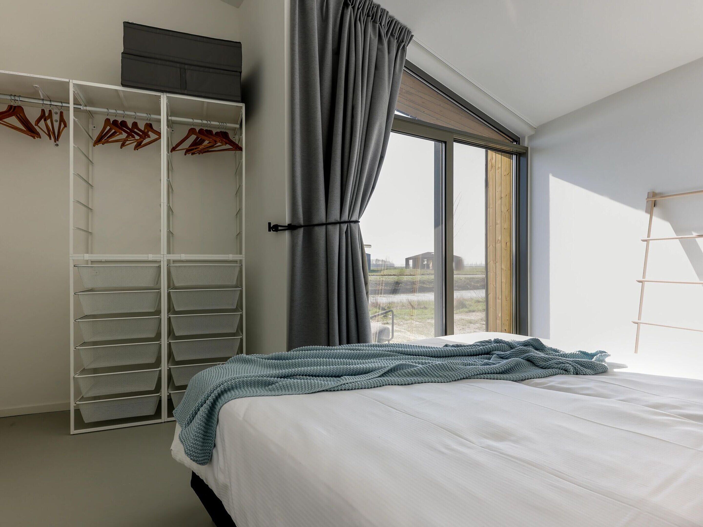 A bedroom with a bed, a wardrobe, and a window with curtains.
