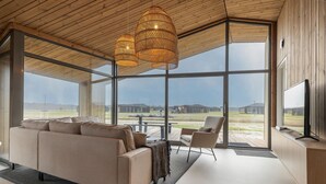 A modern living room with a large sofa, a coffee table, and a TV on a wooden wall. - Lovely Holiday Home in Wissenkerke With Garden (Wissenkerke)