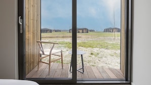 A room with a sliding glass door leading to an outdoor deck with a chair and a small table. - Lovely Holiday Home in Wissenkerke With Garden (Wissenkerke)