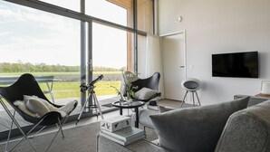 A modern living room with a large window, a telescope, a flat-screen TV, and comfortable seating. - Stylish Countryside Home (Wissenkerke)