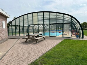 Una piscina scoperta coperta, con tavolo da picnic e sedie a sdraio.