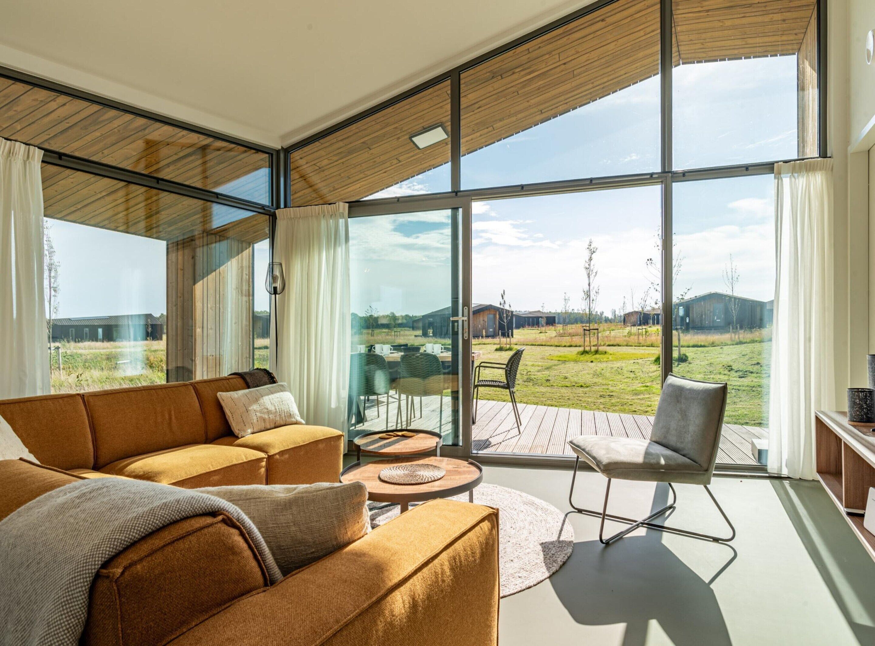 A modern living room with a large glass window, a sofa, a coffee table, and a chair.