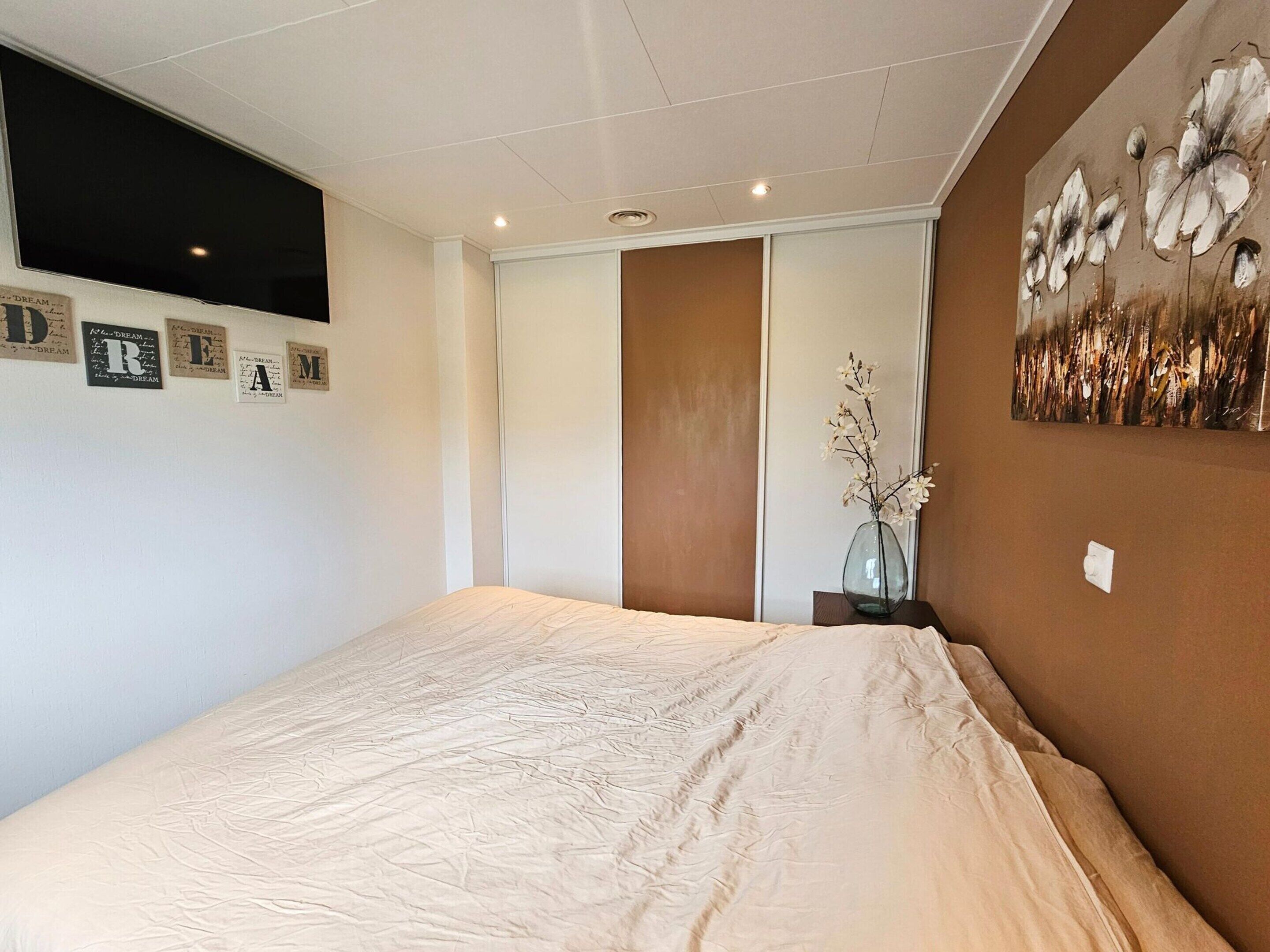 A bedroom with a bed, a window, a door, and a wall with framed letters.