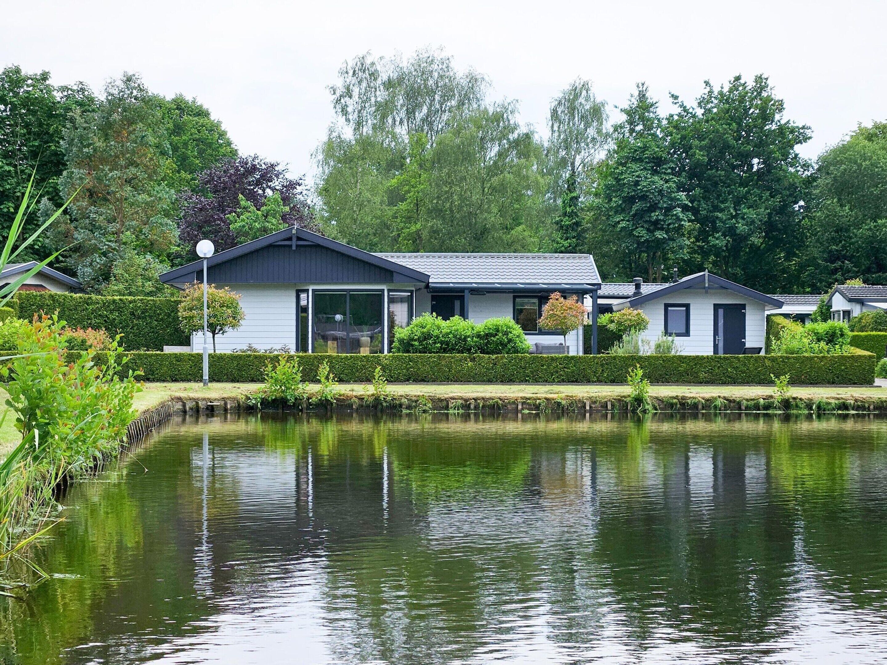 A row of modern, single-story houses with a pond in the foreground.