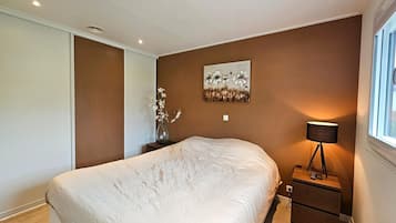 A bedroom with a large bed, a bedside table with a lamp, and a wall-mounted painting.