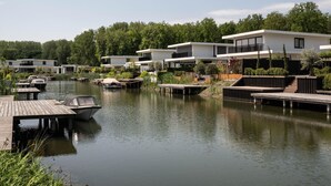En fastighet vid sjön med moderna hus, förtöjda båtar och en träbrygga.