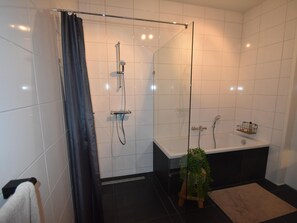 A modern bathroom with a glass shower enclosure, a bathtub, and a small potted plant. - Villa on the Water Near the Veluwemeer (Zeewolde)