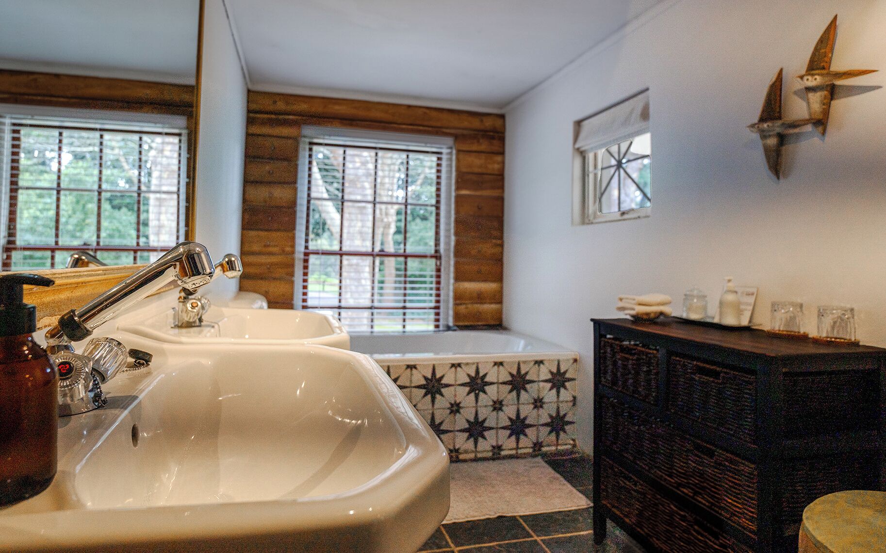 Une salle de bain avec un grand lavabo, une baignoire et un mur en bois.