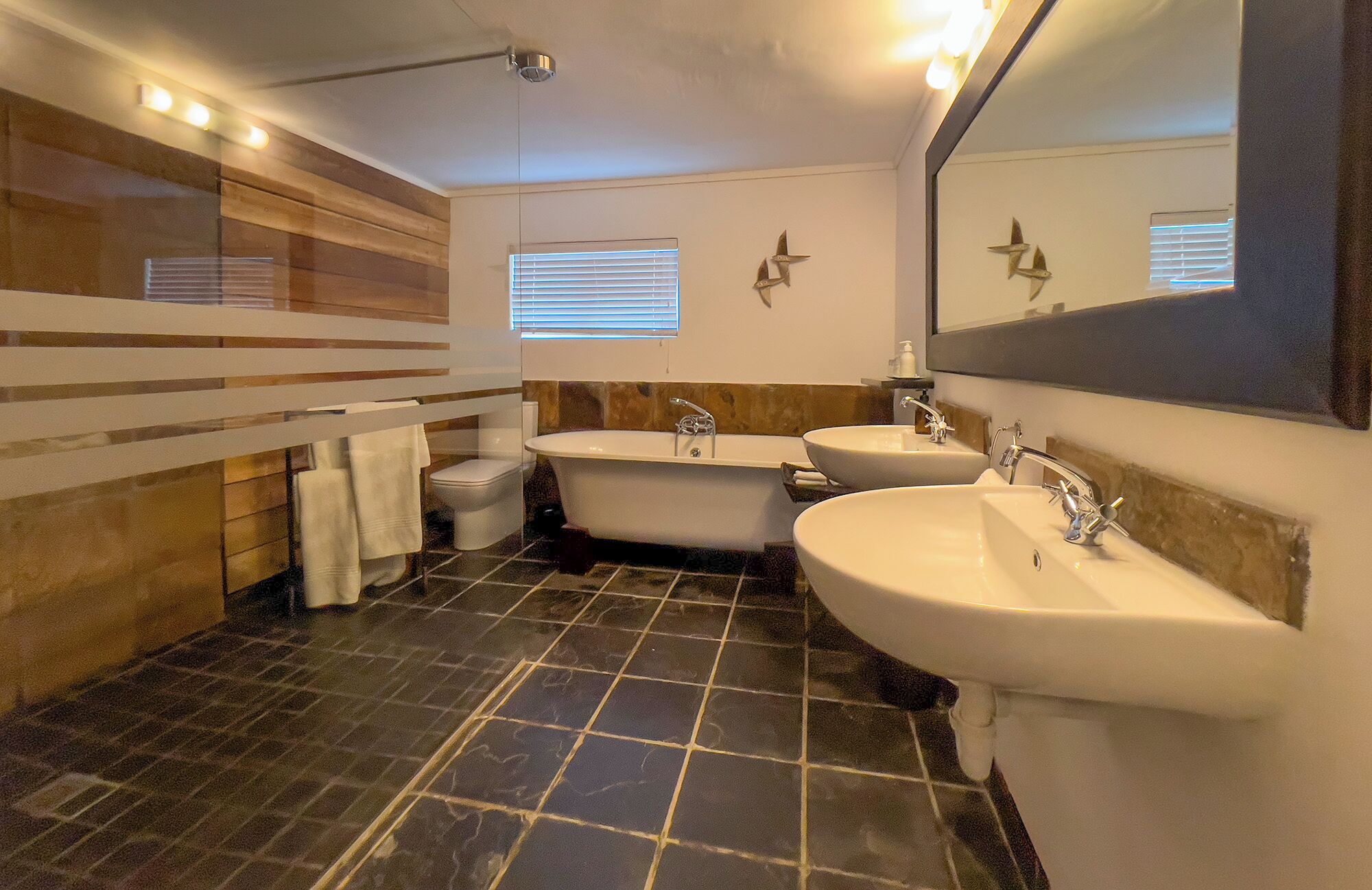 Un baño moderno con bañera, dos lavamanos y un espejo grande.
