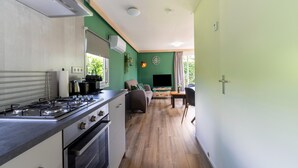 Una cucina compatta con fornello, forno e un'area pranzo con TV e posti a sedere.