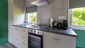 Una cucina compatta con piano cottura a gas, forno e una finestra che offre vista sul verde.