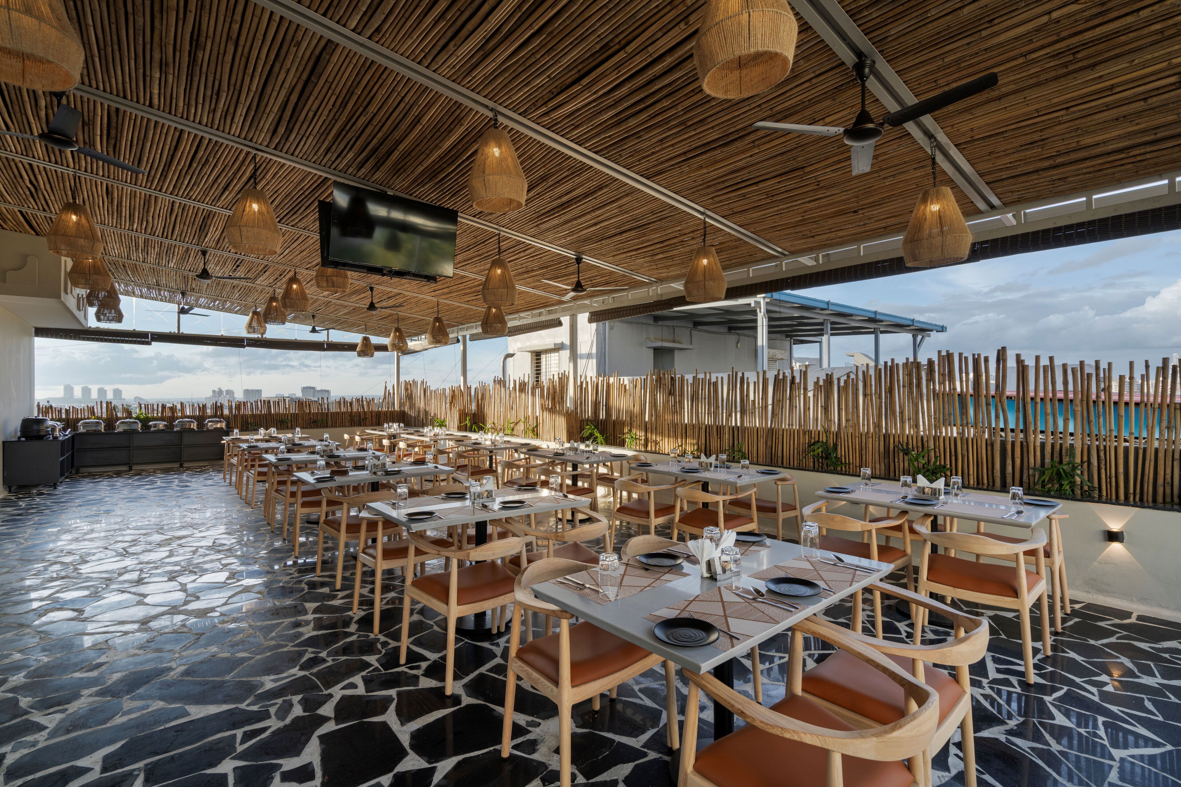 A restaurant with outdoor seating, bamboo ceiling, and a flat-screen TV.