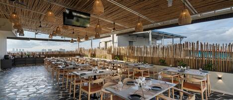 A restaurant with outdoor seating, bamboo ceiling, and a flat-screen TV.