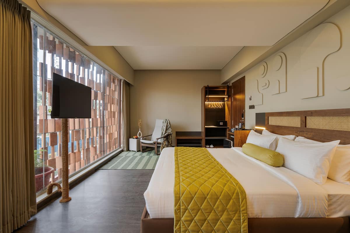 A hotel room with a bed, a chair, a wardrobe, and a television.