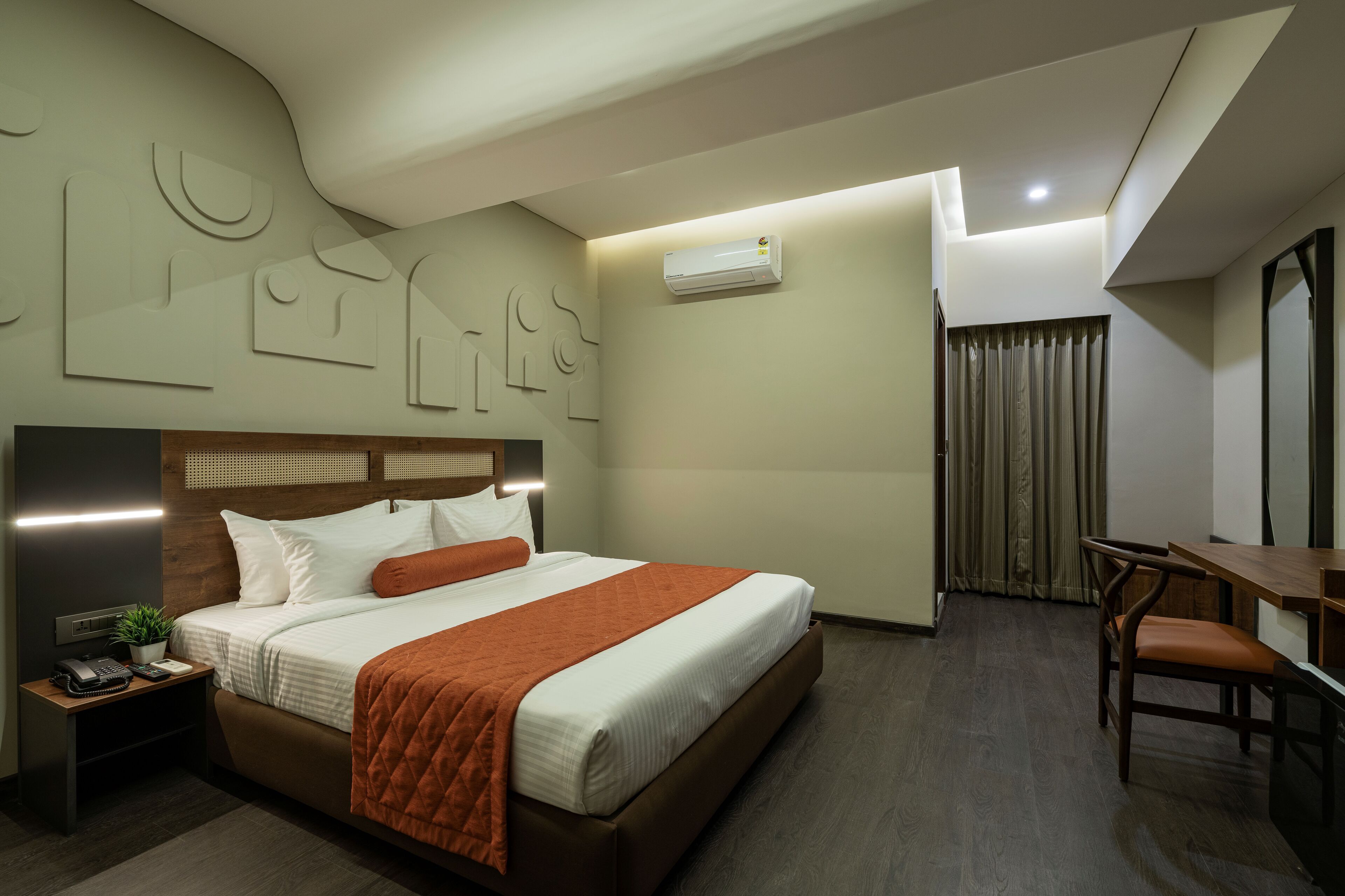 Ein modernes Hotelzimmer mit einem großen Bett, einem Nachttisch und einem Schreibtisch mit Stuhl.