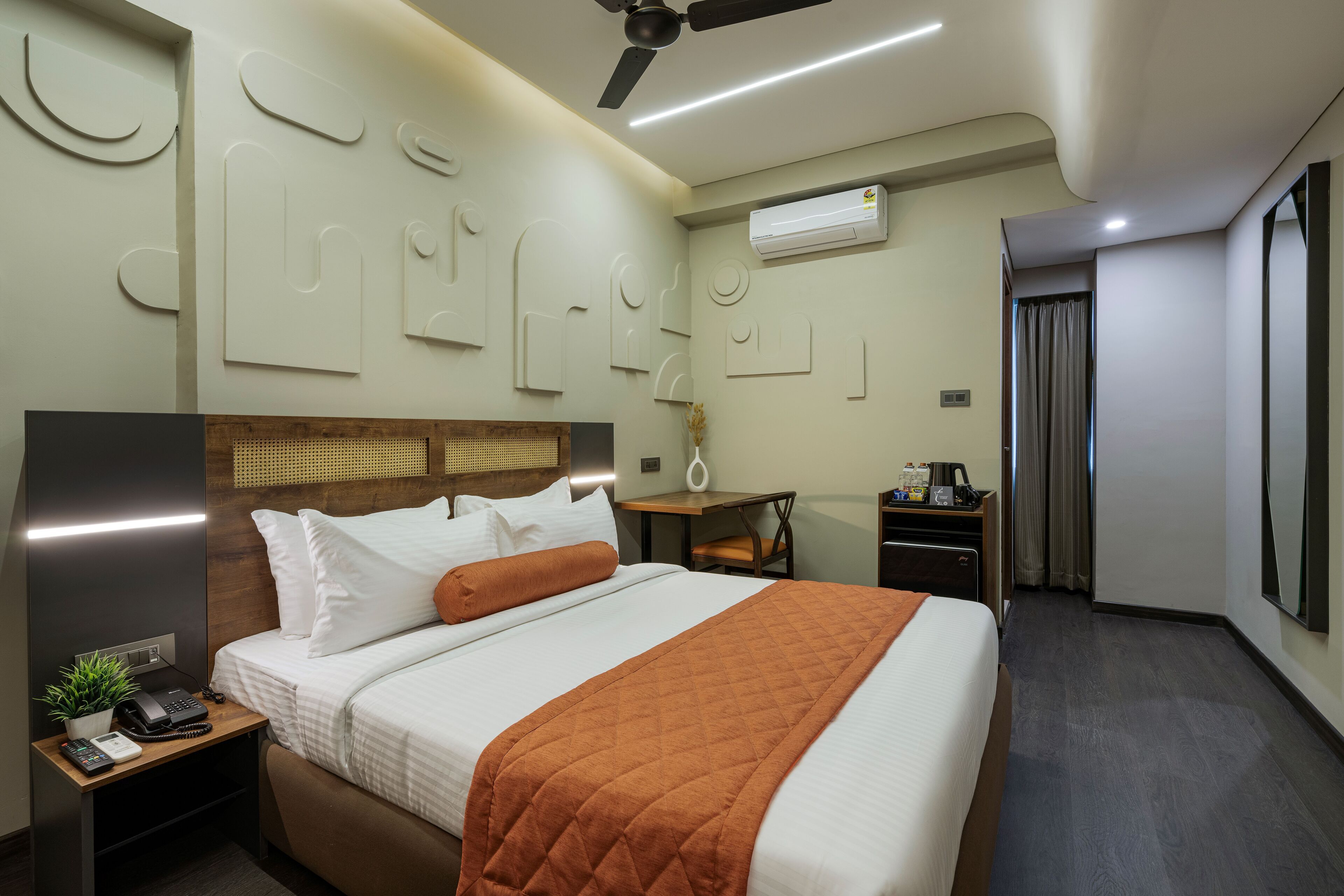 Ein modernes Hotelzimmer mit einem Bett, einem Nachttisch und einem Schreibtisch mit Stuhl.