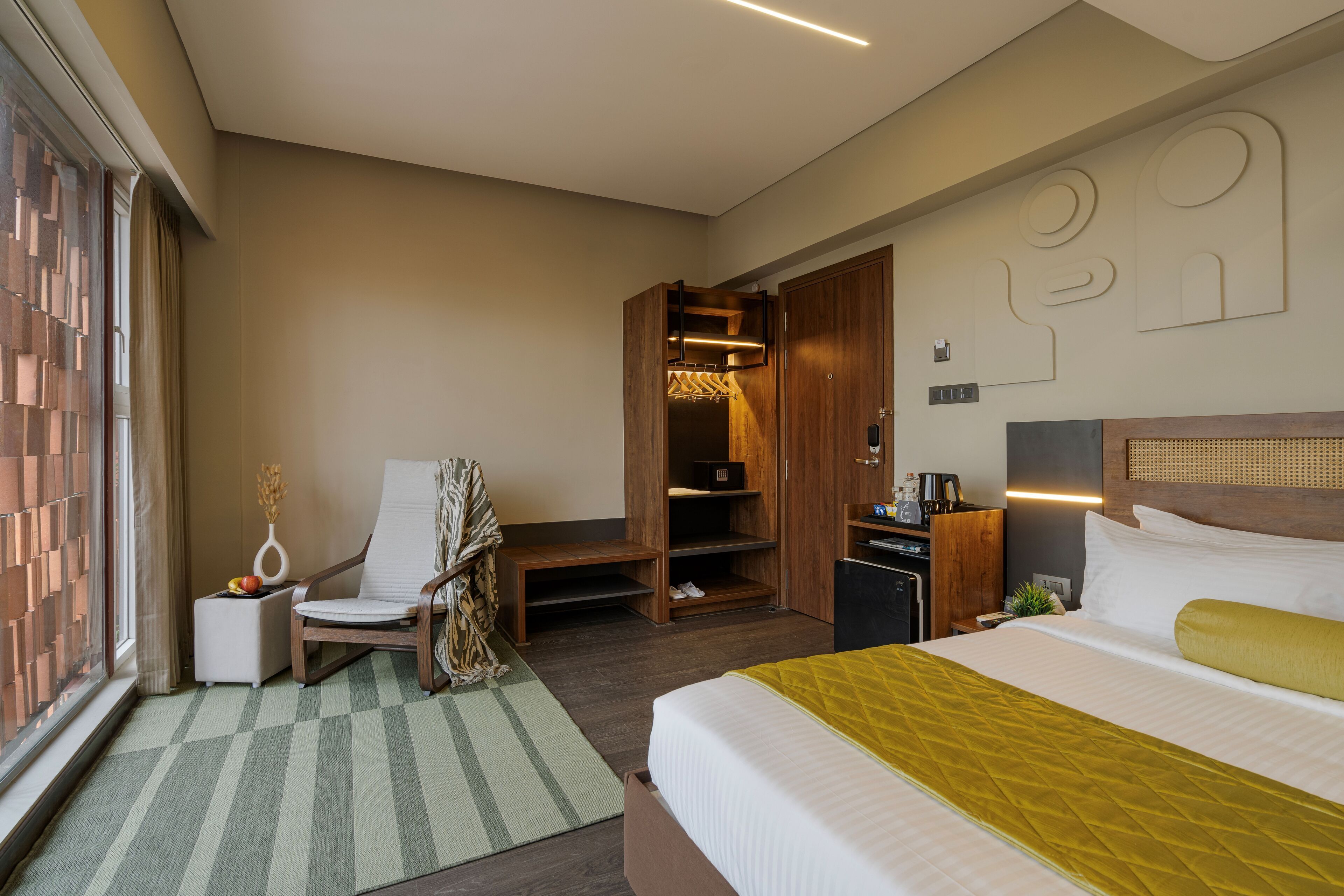 Una habitación de hotel con cama, una silla, un escritorio, un armario y un zapatero.