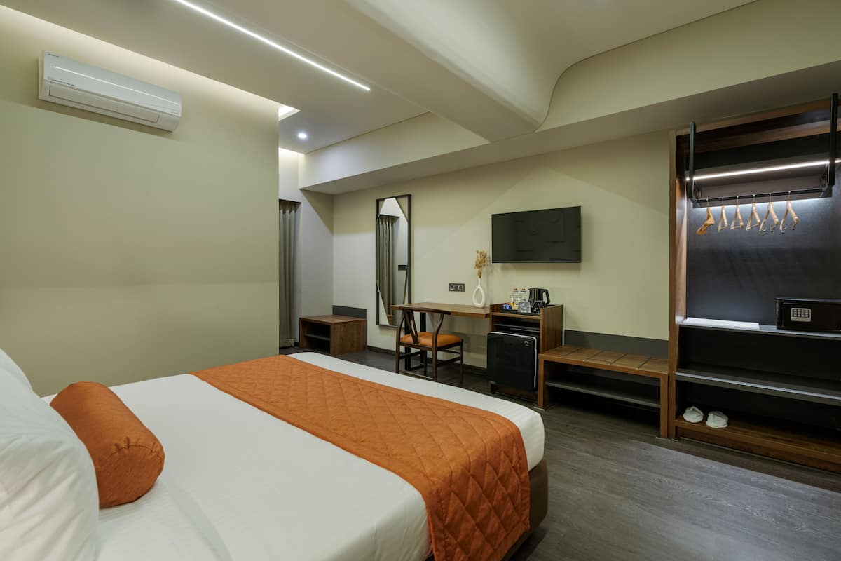 A hotel room with a bed, desk, chair, and a TV mounted on the wall.