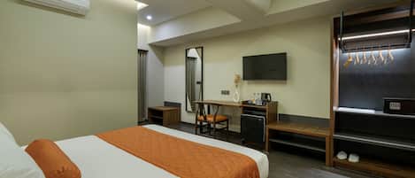 A hotel room with a bed, desk, chair, and a TV mounted on the wall.