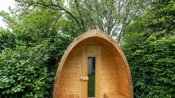 A wooden cabin with a curved roof, a door, and two benches. - Luxury Chalet in Stegeren, Beautiful Surroundings (Stegeren)
