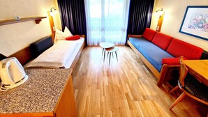 Una habitación de hotel con una cama, un sofá, una mesita y una silla.