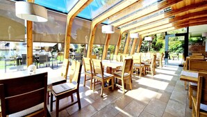 Un comedor interior con mobiliario de madera y ventanas amplias.