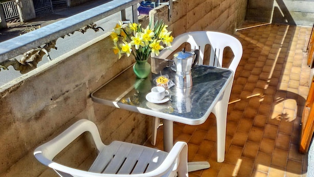 A small outdoor seating area with a table and two chairs, a vase with yellow flowers, and a coffee maker. - Cosy Apartment 200m From the sea (Ravenna)