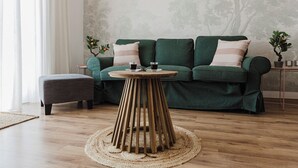 A modern living room with a green sofa, a round wooden table, and a grey ottoman. - Enjoy a stylish experience at this centrally-located place (San Pawl il-Baħar)