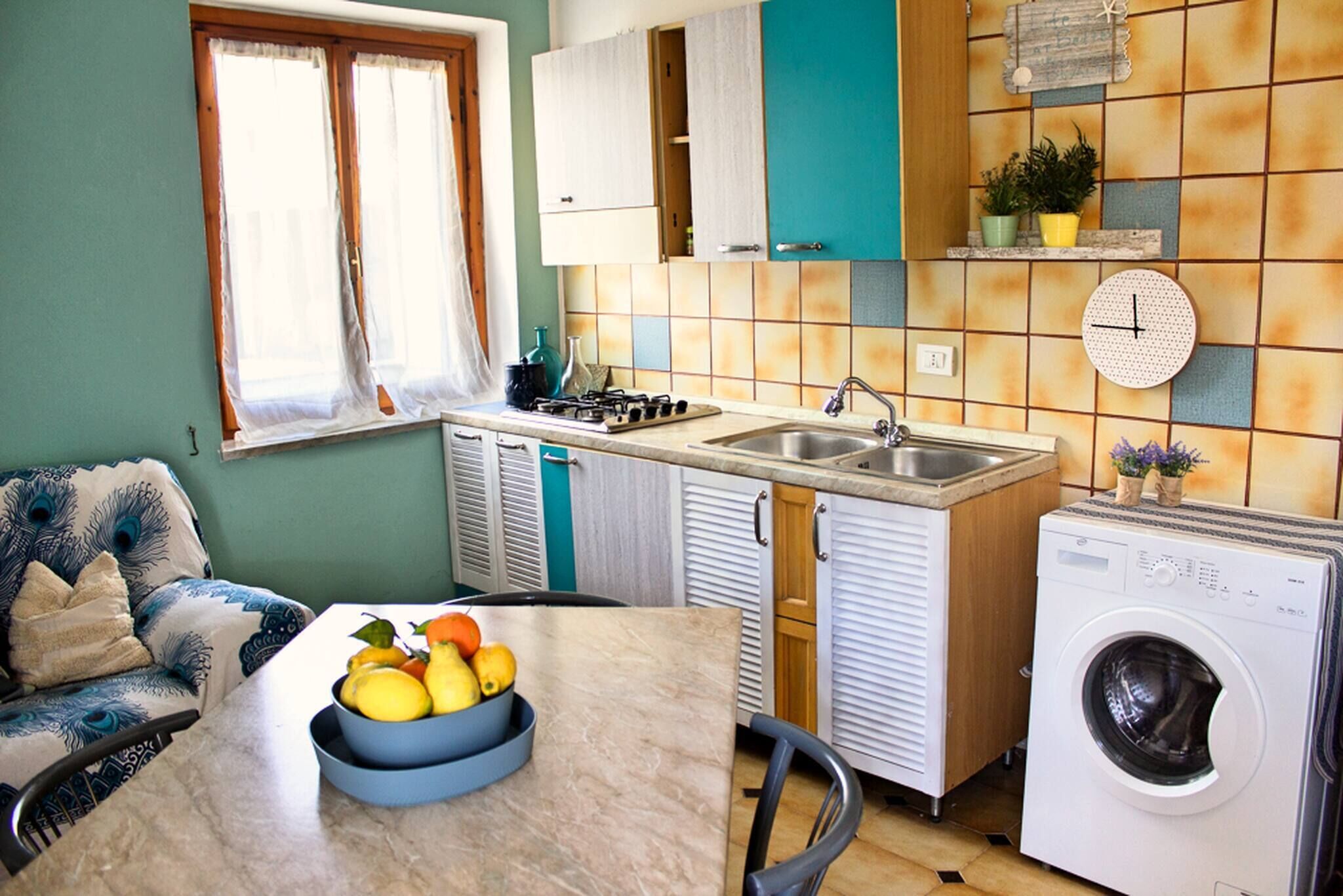 Une cuisine de taille réduite, équipée d’un évier, d’une cuisinière et d’un lave-linge.