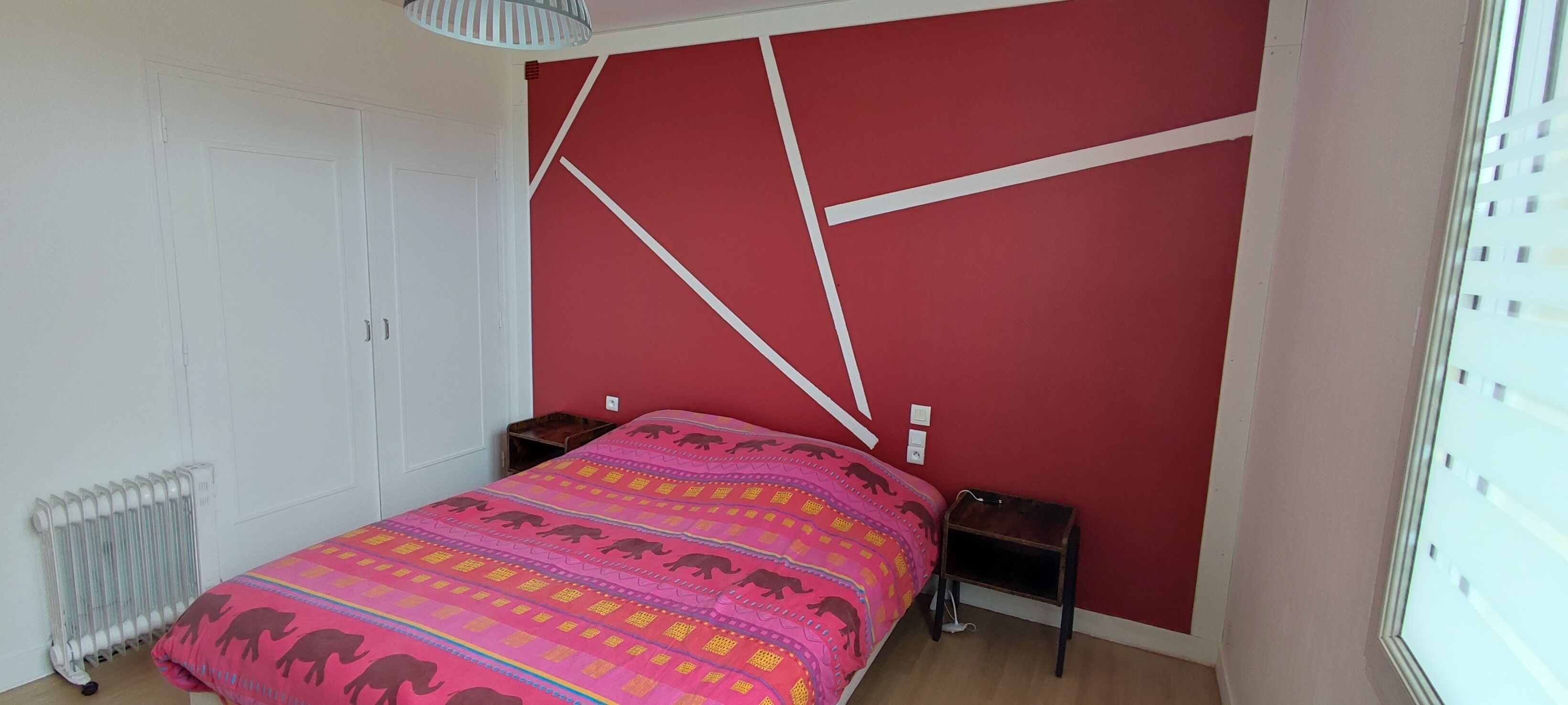 Un dormitorio con cama, mesita de noche, radiador y armario.