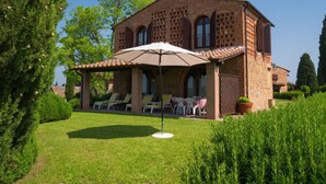 A brick house with a patio area featuring outdoor seating and a large umbrella. - Villa With Terrace and Pool (Montaione)
