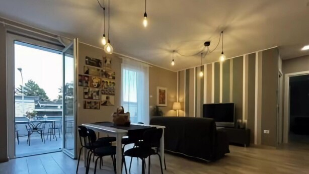 A modern living room with a dining area, featuring a sofa, TV, and a table with chairs.