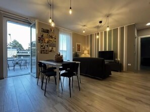 Una sala de estar moderna con comedor, que incluye un sofá, televisor y una mesa con sillas.
