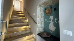 A staircase with a handrail, a wall with a mural, and a light switch.
