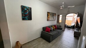 A living room with a grey sofa, colorful cushions, a painting, and a tiled floor. - Centrally located apartment  (Puerto Vallarta)