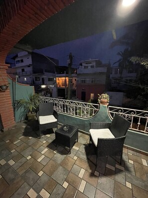 Ein möblierter Patio im Freien mit Korbmöbeln und Fliesenboden.