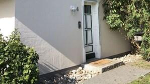 Una casa de un piso con techo de paja, fachada blanca y un pequeño porche.
