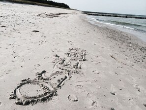 Ein sandiger Strand mit Fußspuren und einem kreisförmigen Muster.