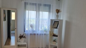 A bedroom with a bed, a wardrobe, a window with sheer curtains, and a bedside table with a plant. - Wohnung im Teutoburger Wald Externsteine (Nieheim)
