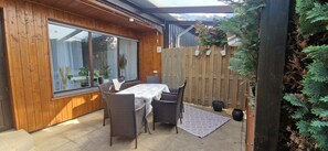 A patio with a table and chairs, a wooden fence, and potted plants. - Wohnung im Teutoburger Wald Externsteine (Nieheim)