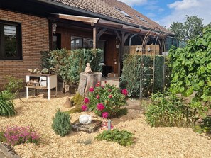 A garden with a variety of plants and flowers, a wooden bench, and a statue. - Wohnung im Teutoburger Wald Externsteine (Nieheim)