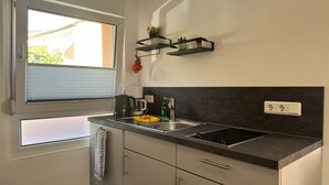A compact kitchen with a window, a sink, a stove, and a countertop. - Ferienwohnung mit Terrasse in Blankenburg (Blankenburg)