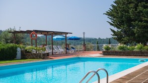 A swimming pool with a wooden deck, lounge chairs, and umbrellas. - Romantic House in Tuscany With Pool Views (Montaione)