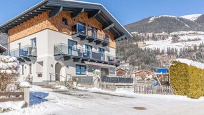 A multi-story building with balconies, a ski slope in the background, and a snowy landscape. - Maximilian 1-2 People (Neukirchen am Grossvenediger)