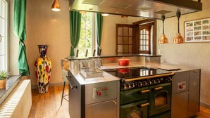 A modern kitchen with a central island, stainless steel appliances, and a view of the outdoors through a window. - Luxurious Villa With Heated Pool (Gesves)