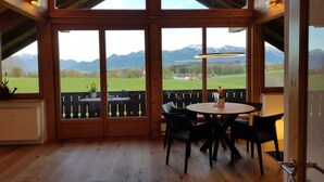 A wooden-paneled room with a large window overlooking a mountainous landscape. - Mountain View Comfortable Holiday Residence (Rimsting)