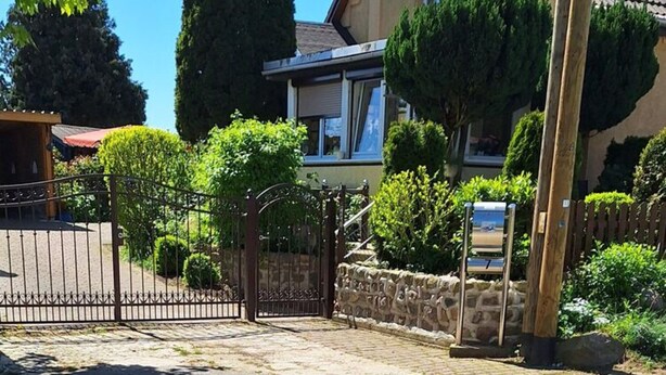 Une entrée fermée par un portail, avec un mur en pierre et un portail en bois.