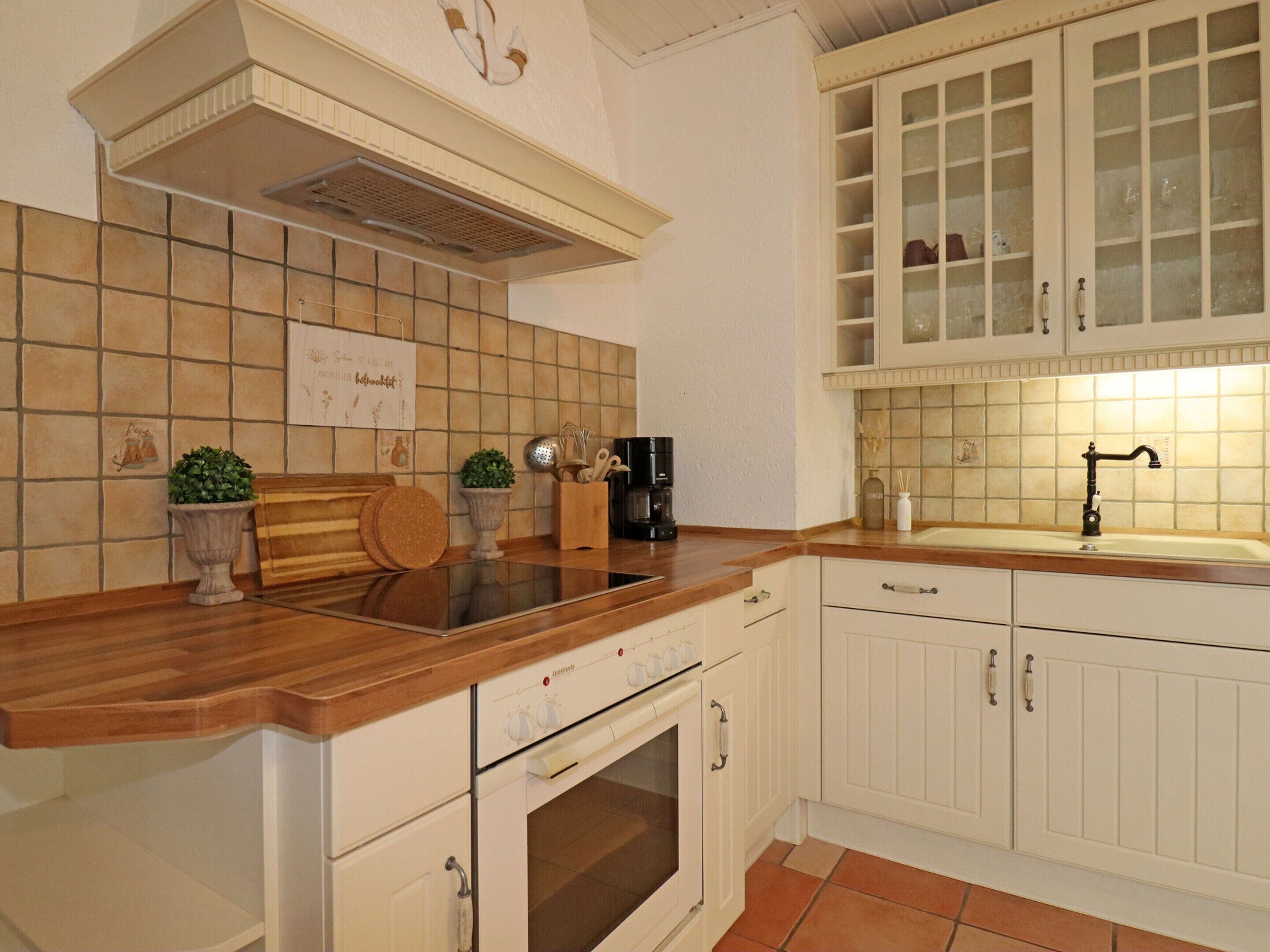 A kitchen with white cabinets, a wooden countertop, a stove, and a sink.
