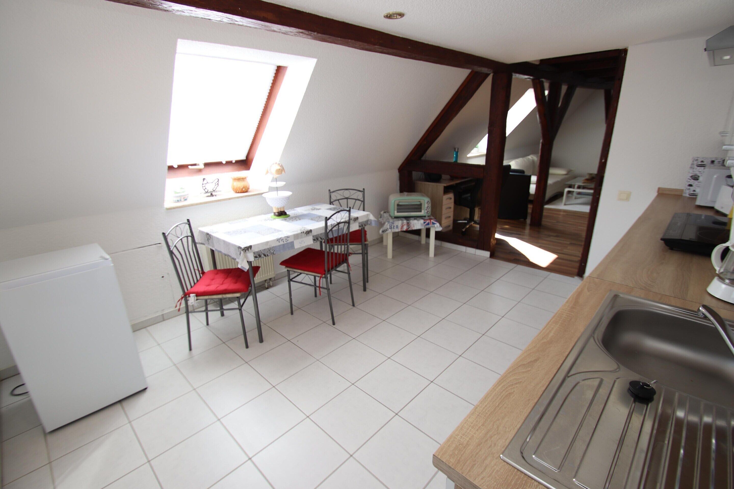 A kitchen with a dining table, chairs, a refrigerator, and a window.