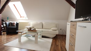 A living room with a white sofa, a glass coffee table, a white cabinet, and a flat-screen TV. - Behagliche Ferienwohnung in Elbingerode (Oberharz am Brocken)